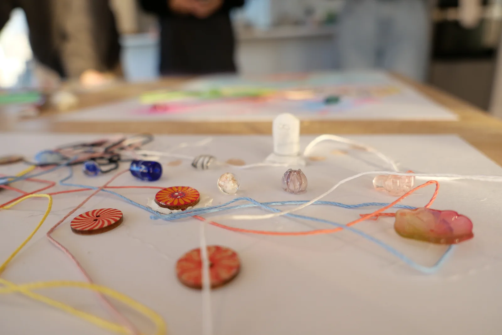 Threads, patterned buttons and glass beads on the workshop table.
